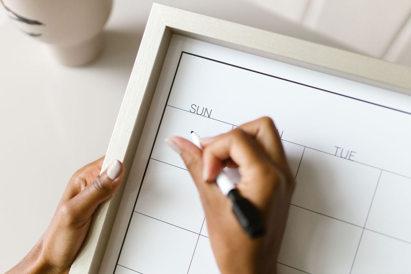 Hands marking dates on a wall calendar