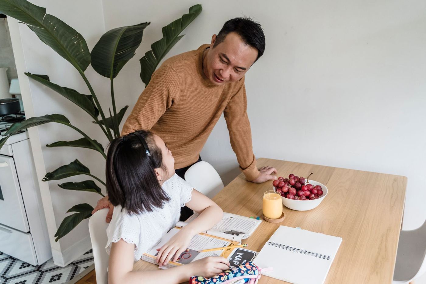 A father helping his daughter with homework at the kitchen table